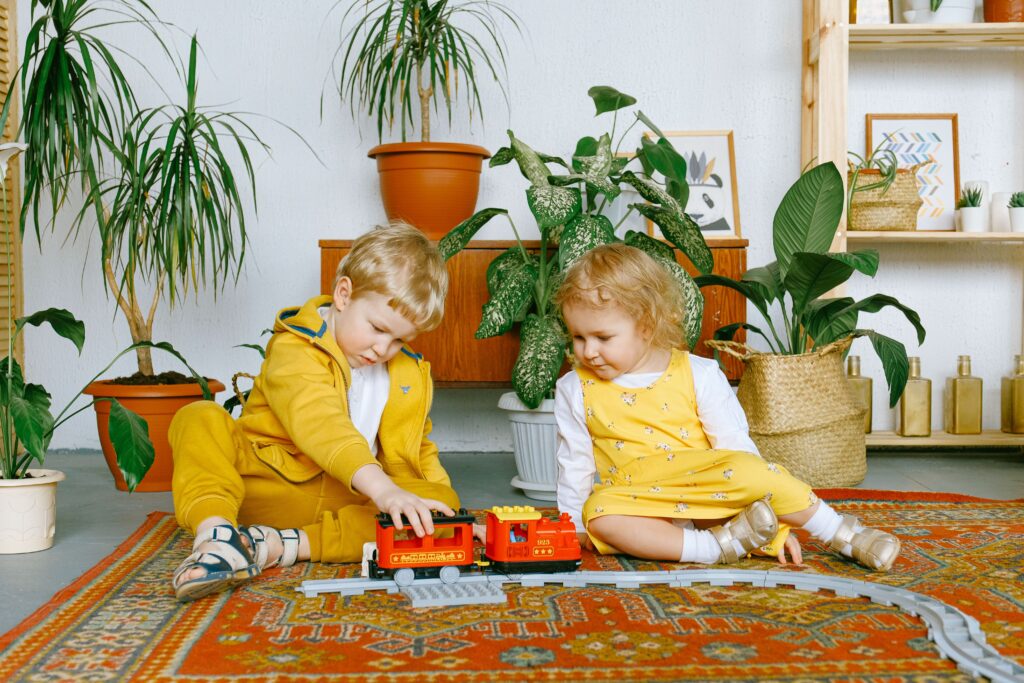 Crianças brincando concentradas com um trem de brinquedo no tapete, exemplo de interesse intenso como o hiperfoco no autismo